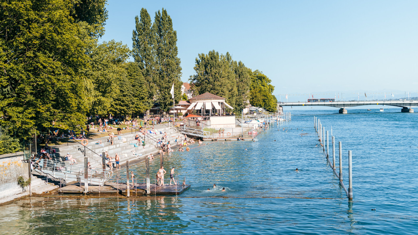 Originalfoto des Rheinstrandbads Konstanz mit Badegästen am Seerhein, Sonnenterrasse und Fahrradbrücke