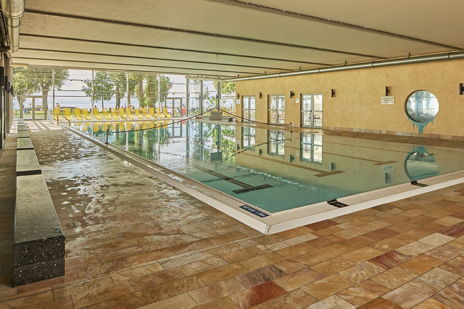 Originalfoto des 25-Meter-Hallenbeckens im Aquastaad Immenstaad mit Blick durch die Glasfront zum Bodensee.