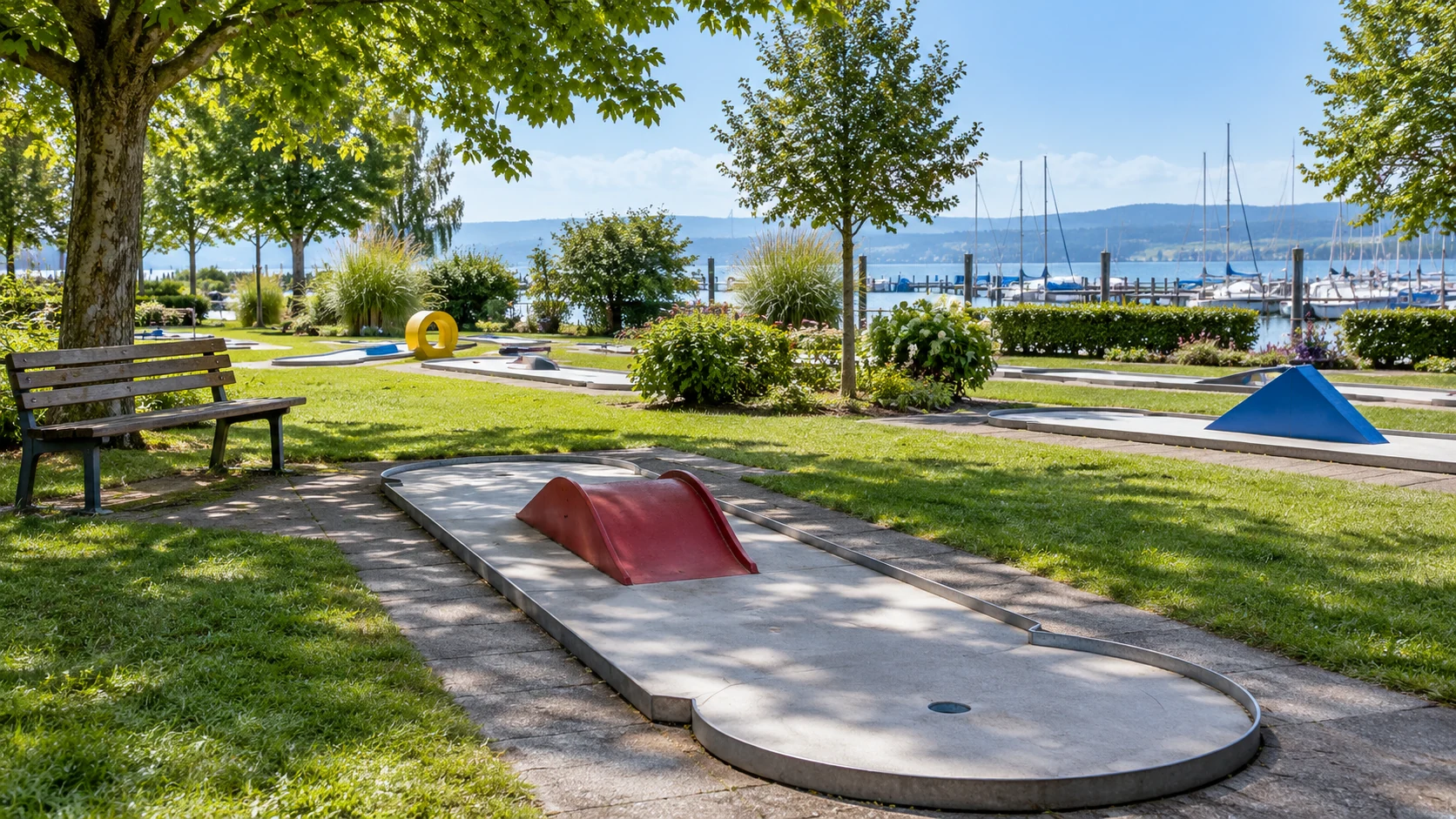 KI-Illustration: Klassische Minigolfbahnen, Sitzbank und Rasenfläche; Hafenmasten hinter der Anlage; Minigolf Hard in Hard