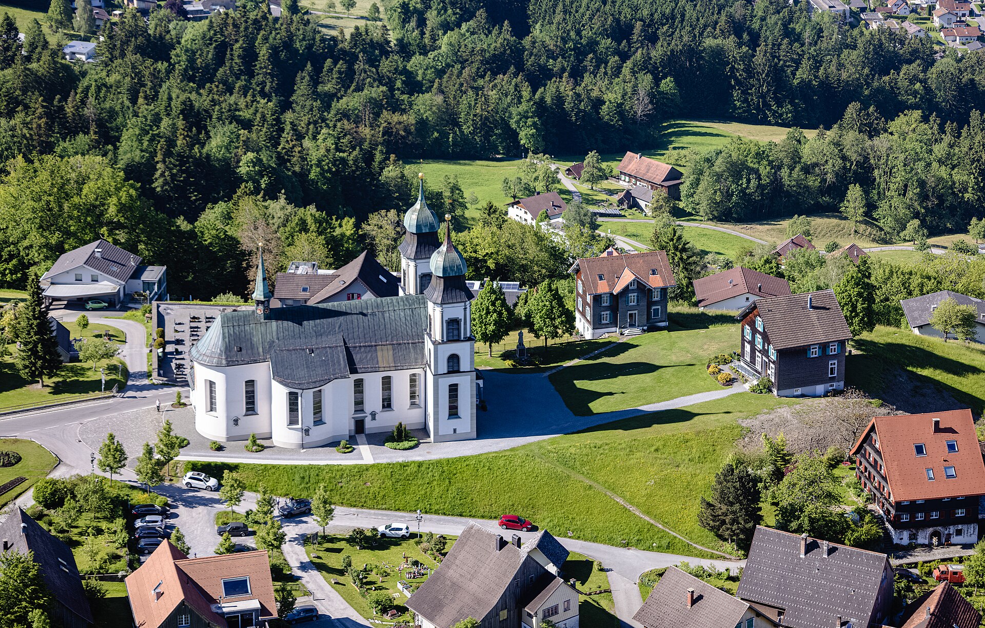 Helle Luftaufnahme der Basilika Maria Bildstein mit Pfarrhaus und Wiesen