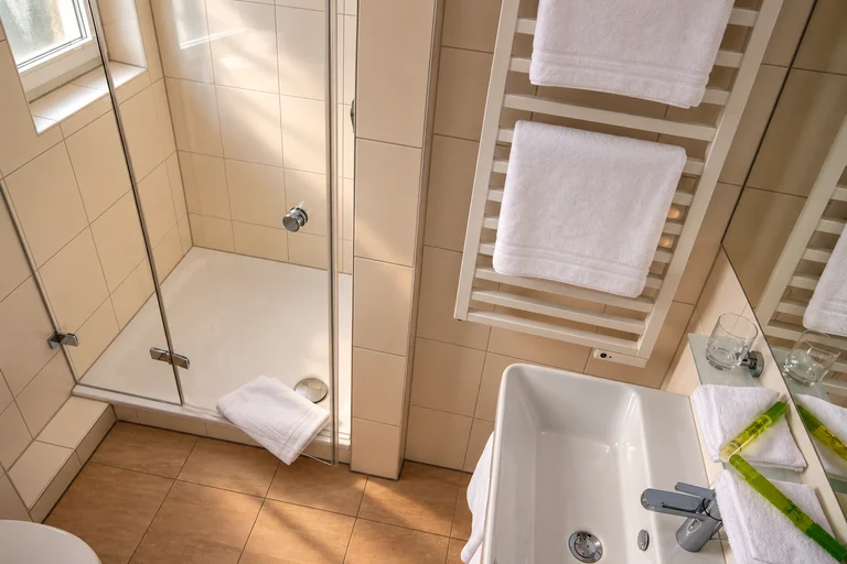 Bad mit Dusche und Handtuchheizkörper im Hotel Lindenallee