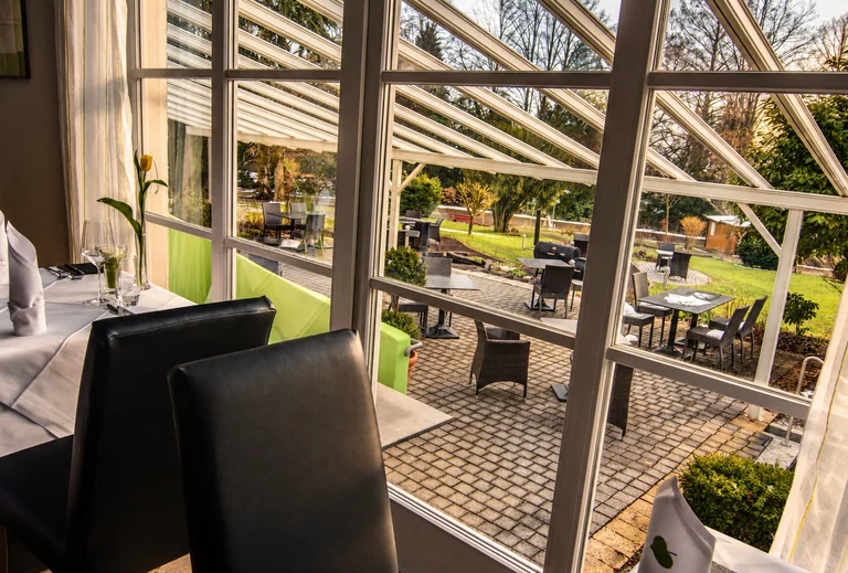 Blick vom Wintergarten auf die Terrasse im Hotel Lindenallee