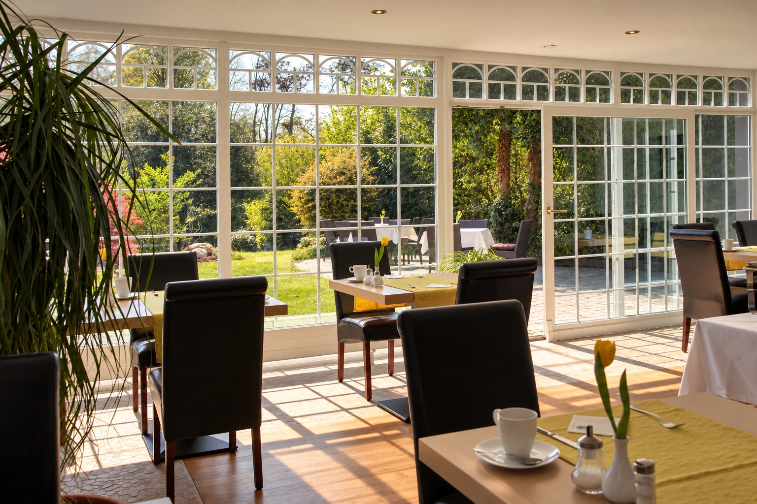 Sonnenlicht im Frühstücksraum mit Blick in den Hotelgarten