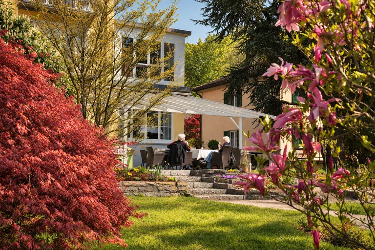 Sitzplätze zwischen blühenden Gehölzen im Hotel Lindenallee